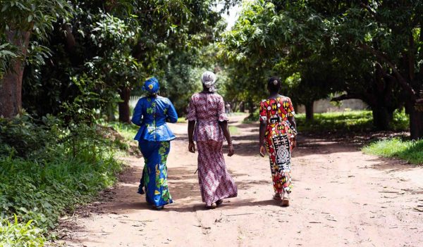 Rear view of three African women walking on a dirt road 