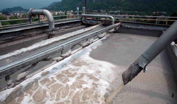 Close-up of pipes empting manufactring waste water into a tank.