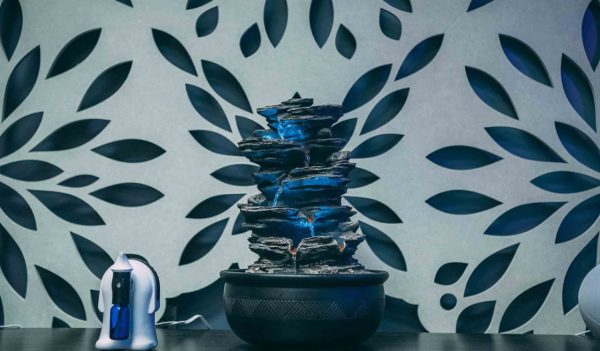 Close-up of a water feature and diffuser used in a multisensory room with patterned wallpaper in  the background.