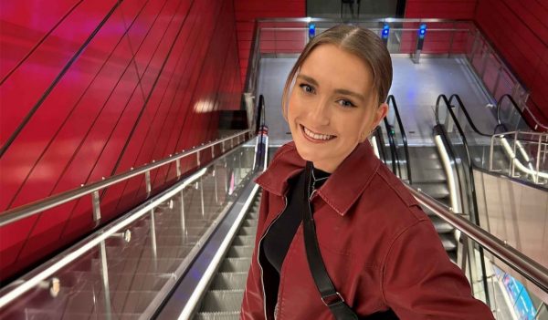 Lydia Connel on an escalator, surrounded by red walls.