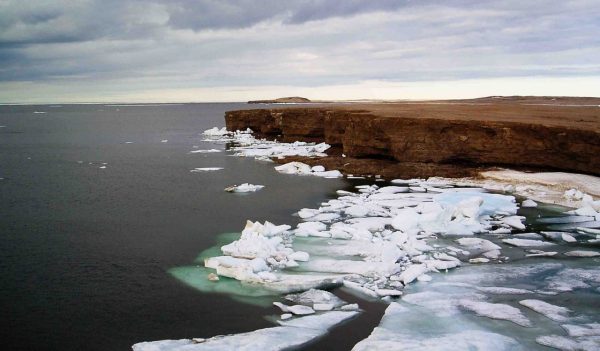 Nunavut coastline - cliff ending at the ocean with ice in the water.