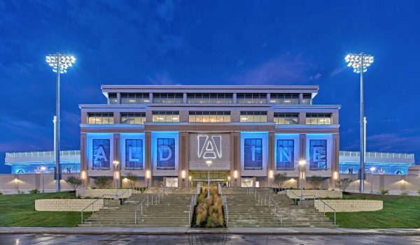 Exterior front entrance with "Aldine" spelled out in blue lights and a large staircase leading to the etrance.