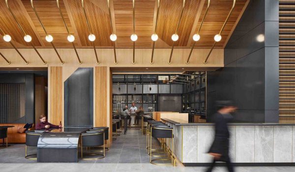 Interior lobby bar with wood ceiling, custom lighting and black leather chairs with brass accents.