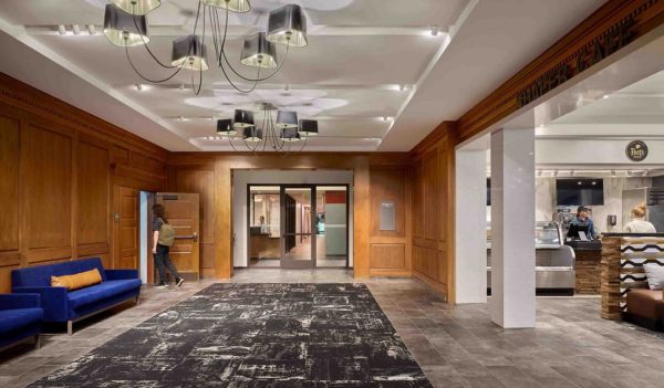 Lobby area with wood paneling and bright blue sofas with a cafe area to the right.