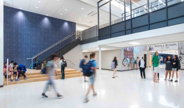 Interior of school with a large staircase with a blue feature wall going to an upper level with students walking around.